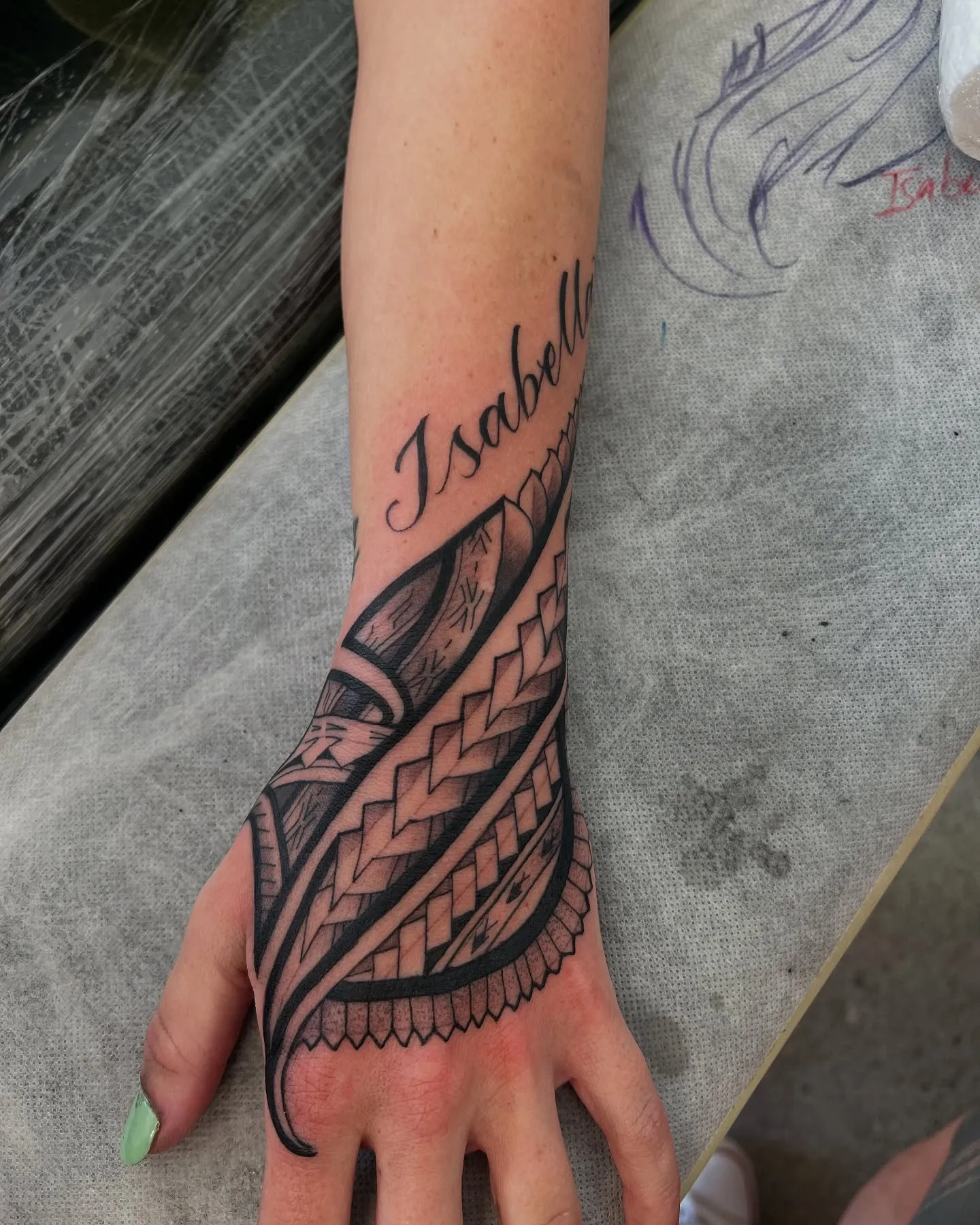 Polynesian tatau running from forearm to hand, with script lettering