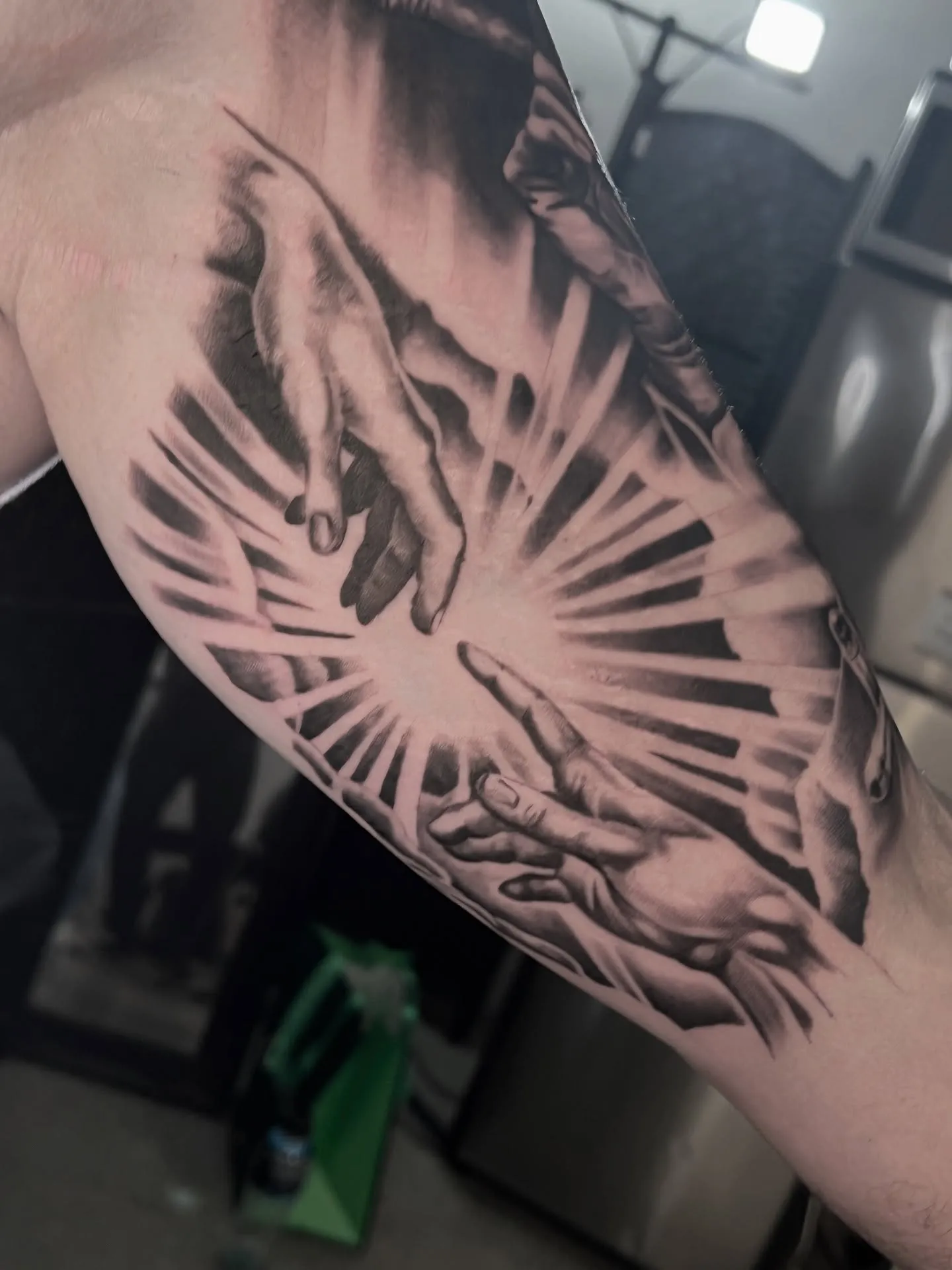 Black and grey piece of hands reaching toward rays of light